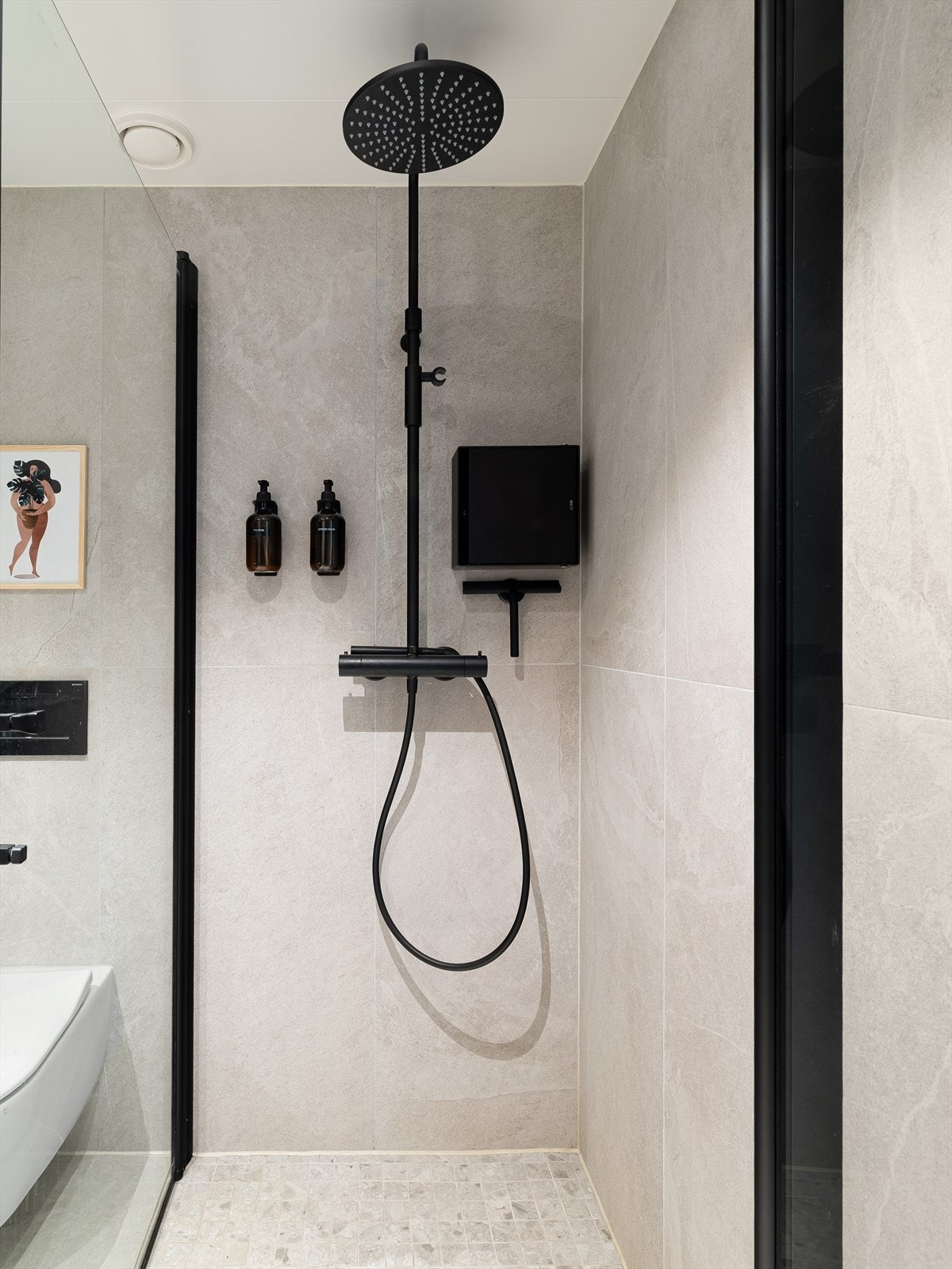 Badet er utstyrt med innfellbare dusjdører, mekanisk avtrekk, rørfordelingsskap, stoppekran og veggmontert wc. Galleribilde