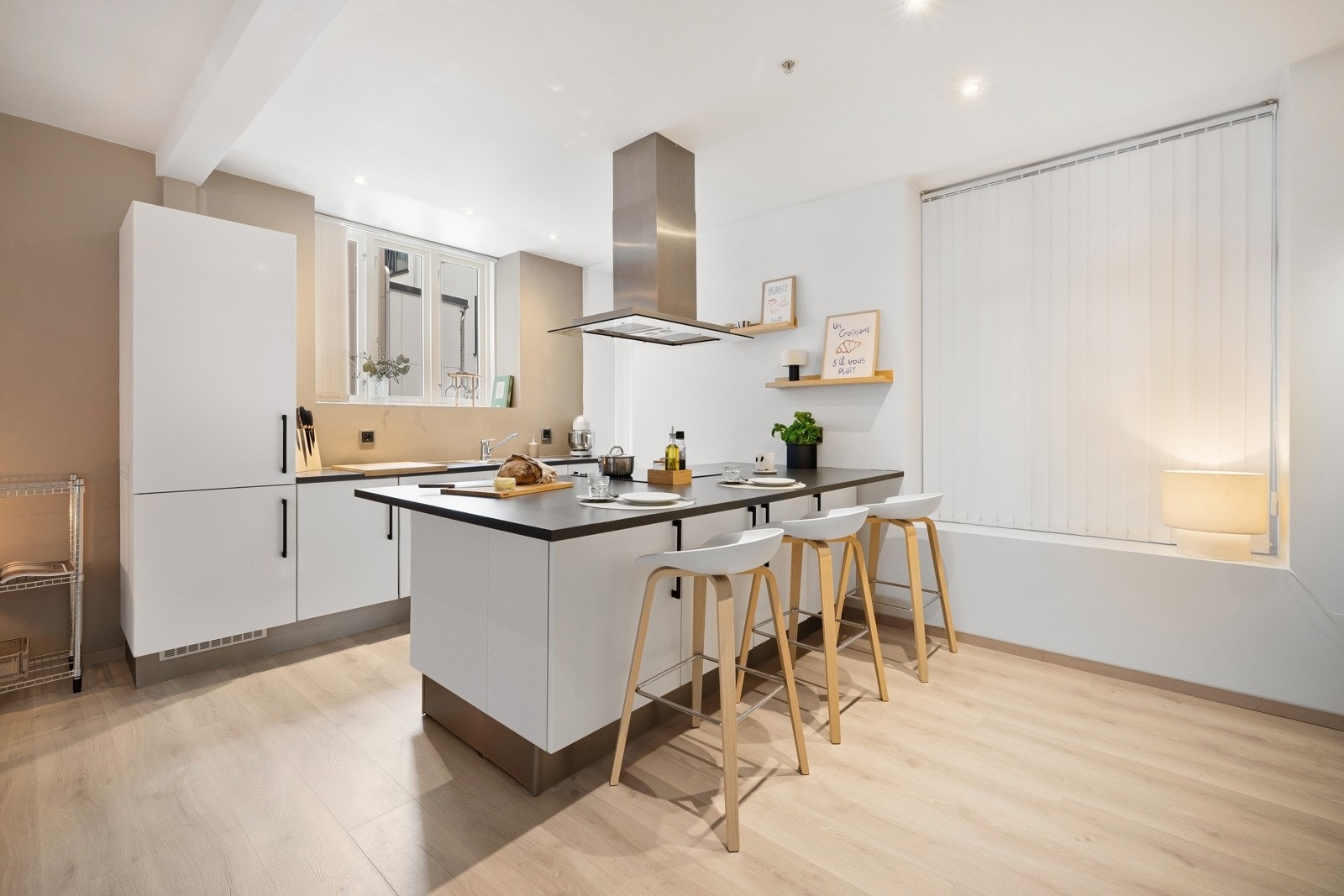 Kjøkkenet har innredning med hvite glatte fronter og egen kjøkkenøy. Det er godt med arbeidsplass på benkeplaten Galleribilde