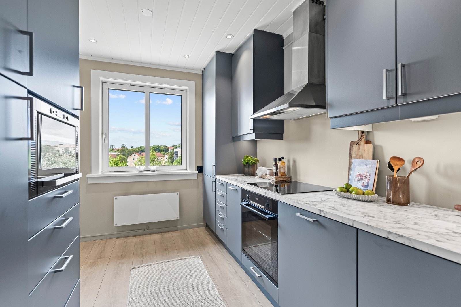 Stilrent kjøkken med grå, glatte fronter og laminert benkeplate i tidløs marmordesign. Galleribilde