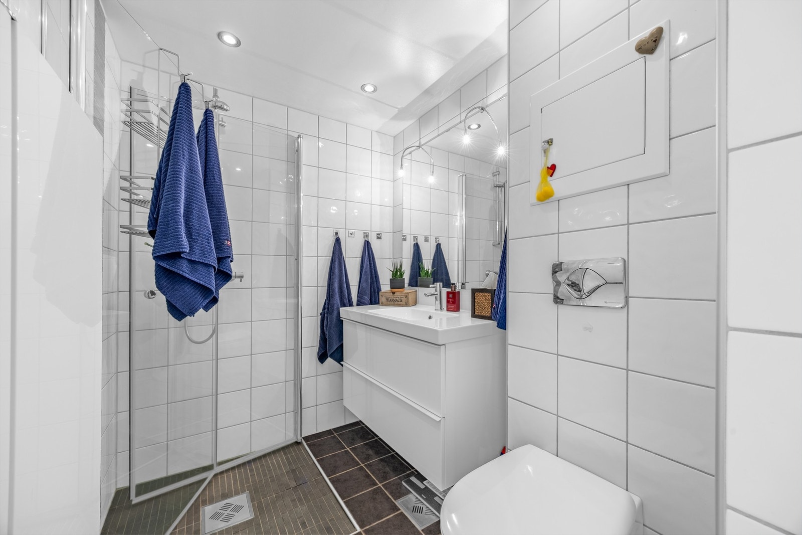 Flislagt baderom fra 2010, med termostatstyrte varmekabler på gulv og downlights i himling. Nedsenket dusjsone med svingdører i glass. Galleribilde