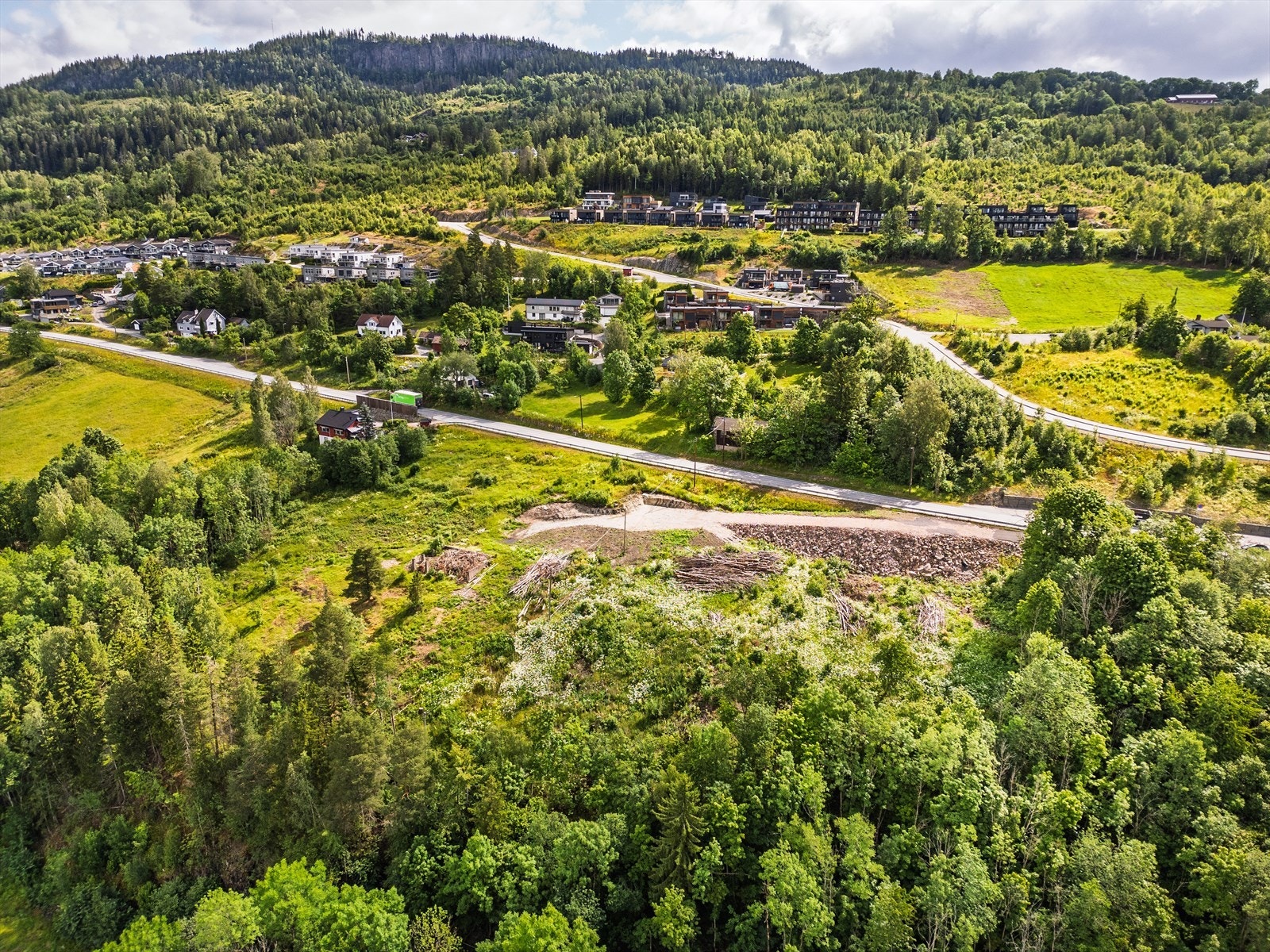 Stor rå tomt med to gnr/bnr beliggende i et skrånende terreng. Flere trær på tomten er hugget ned for klargjøring samt at man har begynt med infrastrukur inn til tomtene Galleribilde