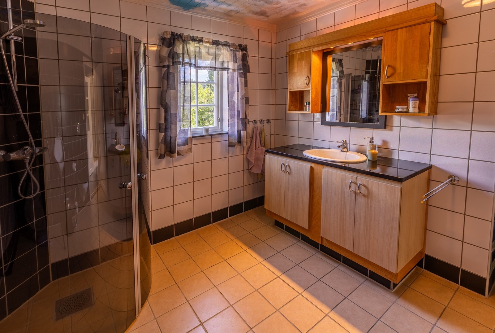Badet har flislagt gulv med elektriske varmekabler. Foliert innredning med benkeplate i stein og nedfelt servant. Dusjhjørne Galleribilde
