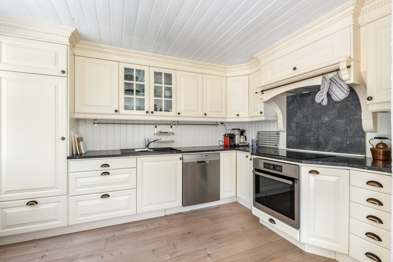 Kjøkkenet er av typen herregårdskjøkken, med laminat på gulvet og hvitmalte vegger - en kombinasjon av synlig tømmer og panel. Galleribilde