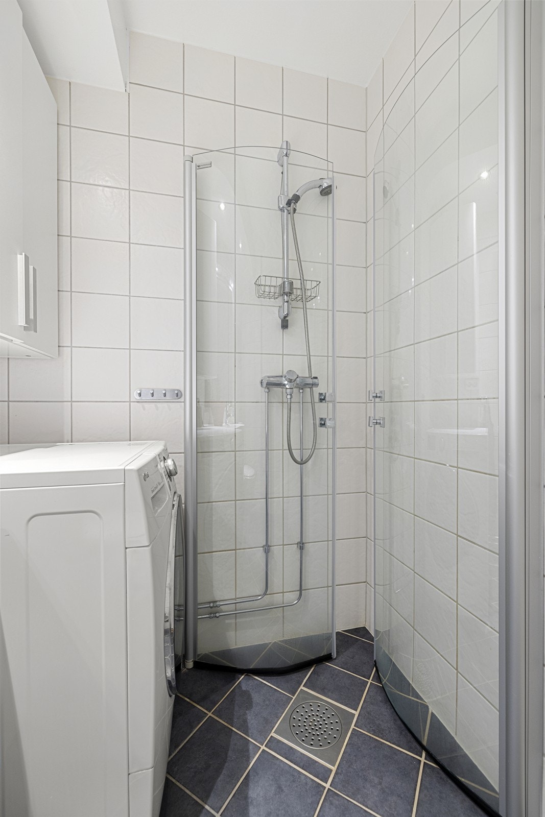 Badet er flislagt med dusjhjørne og opplegg for vaskemaskin. Galleribilde
