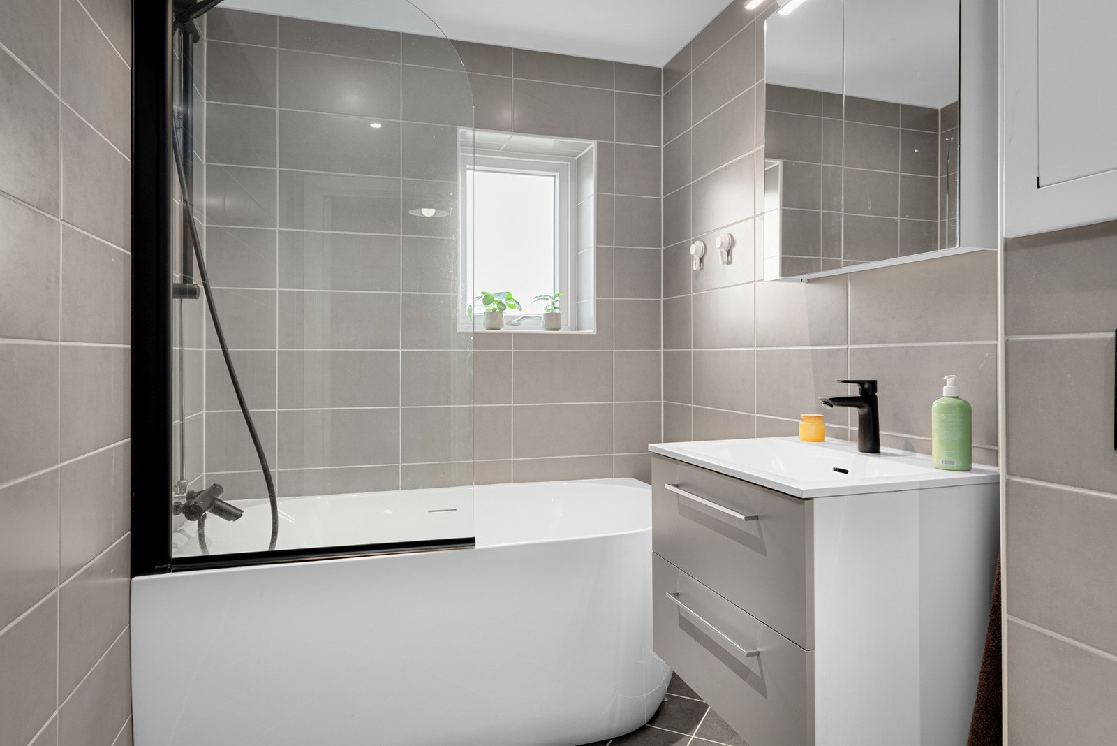 Badekar med innfellbar glassvegg og stilrene fliser gir et rent og moderne uttrykk. Galleribilde