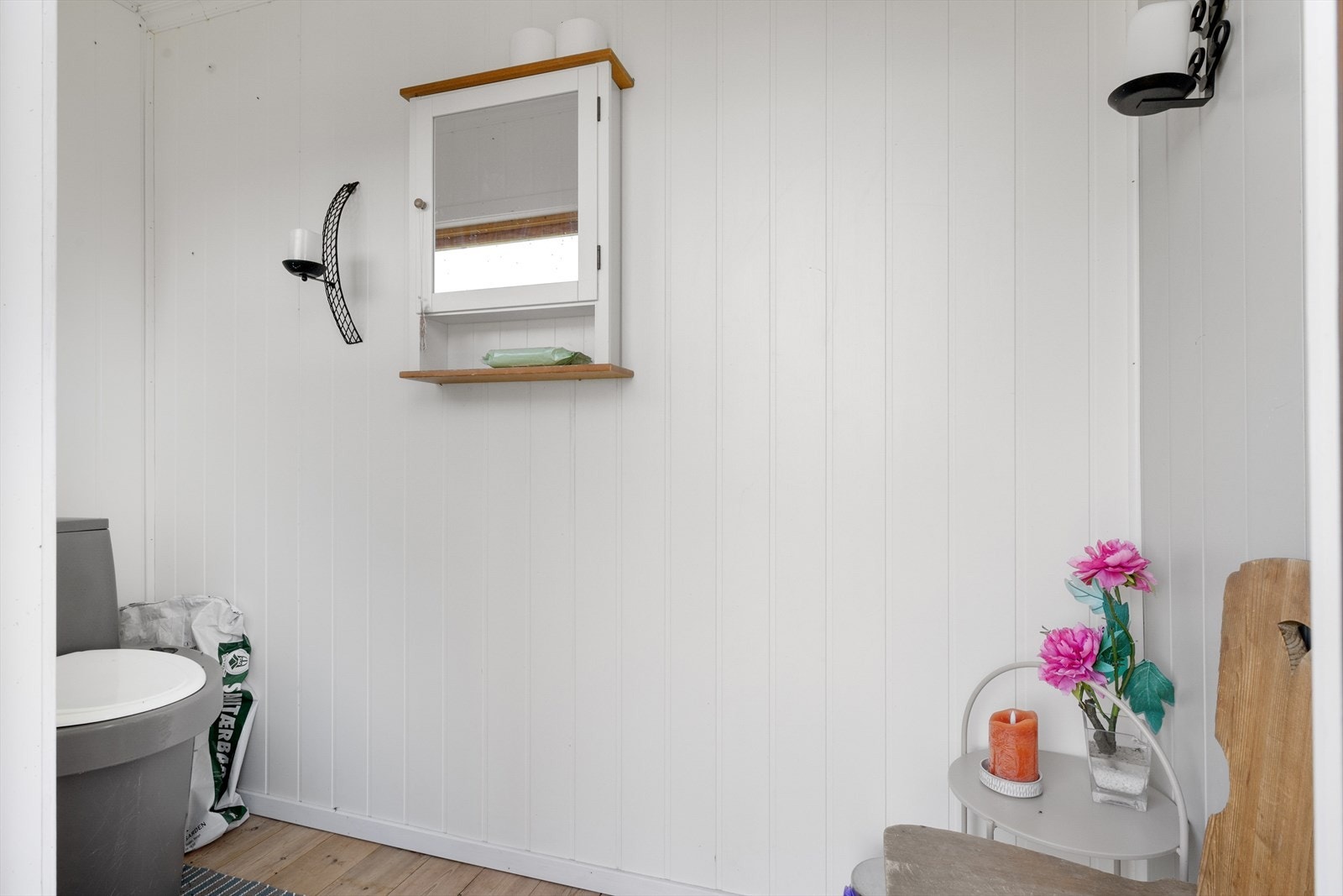 Utedoen i uthuset er malt i lyse farger. Galleribilde