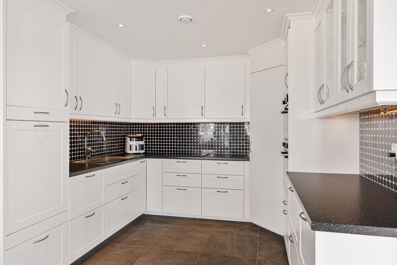 Kjøkkenet har integrerte hvitevarer og godt med lagringsplass i skuffer og skap Galleribilde