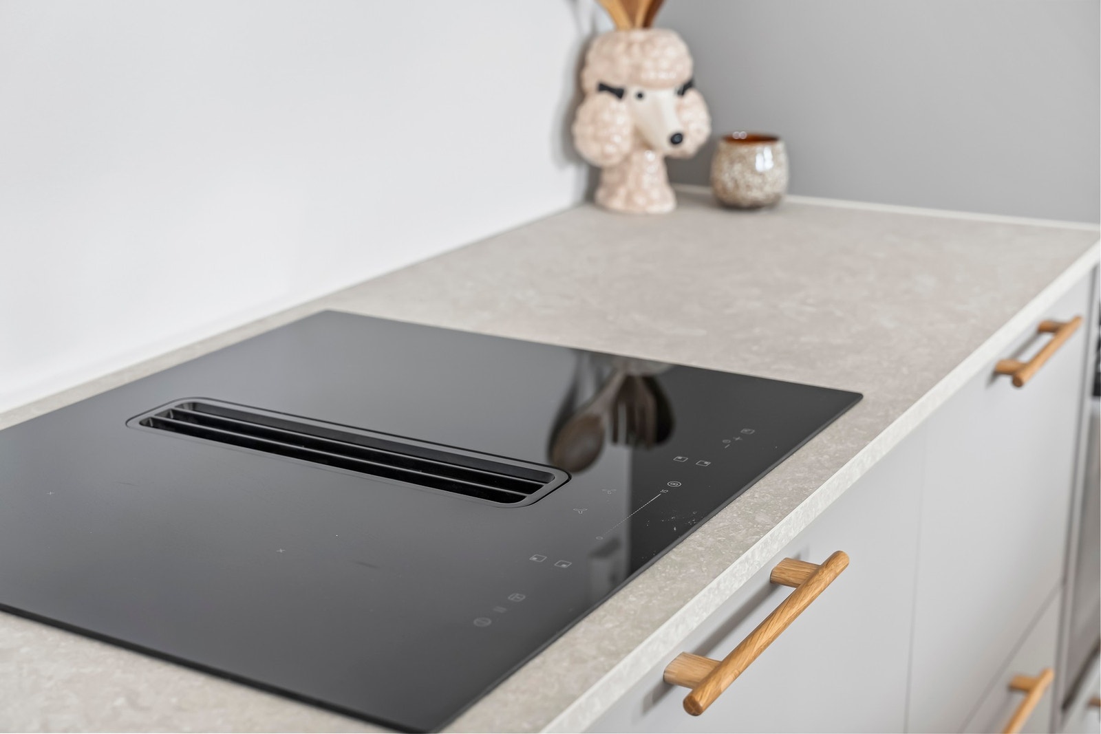 Integrert induksjonstopp med innebygd ventilator, praktisk plassert i den lyse benkeplaten. Galleribilde