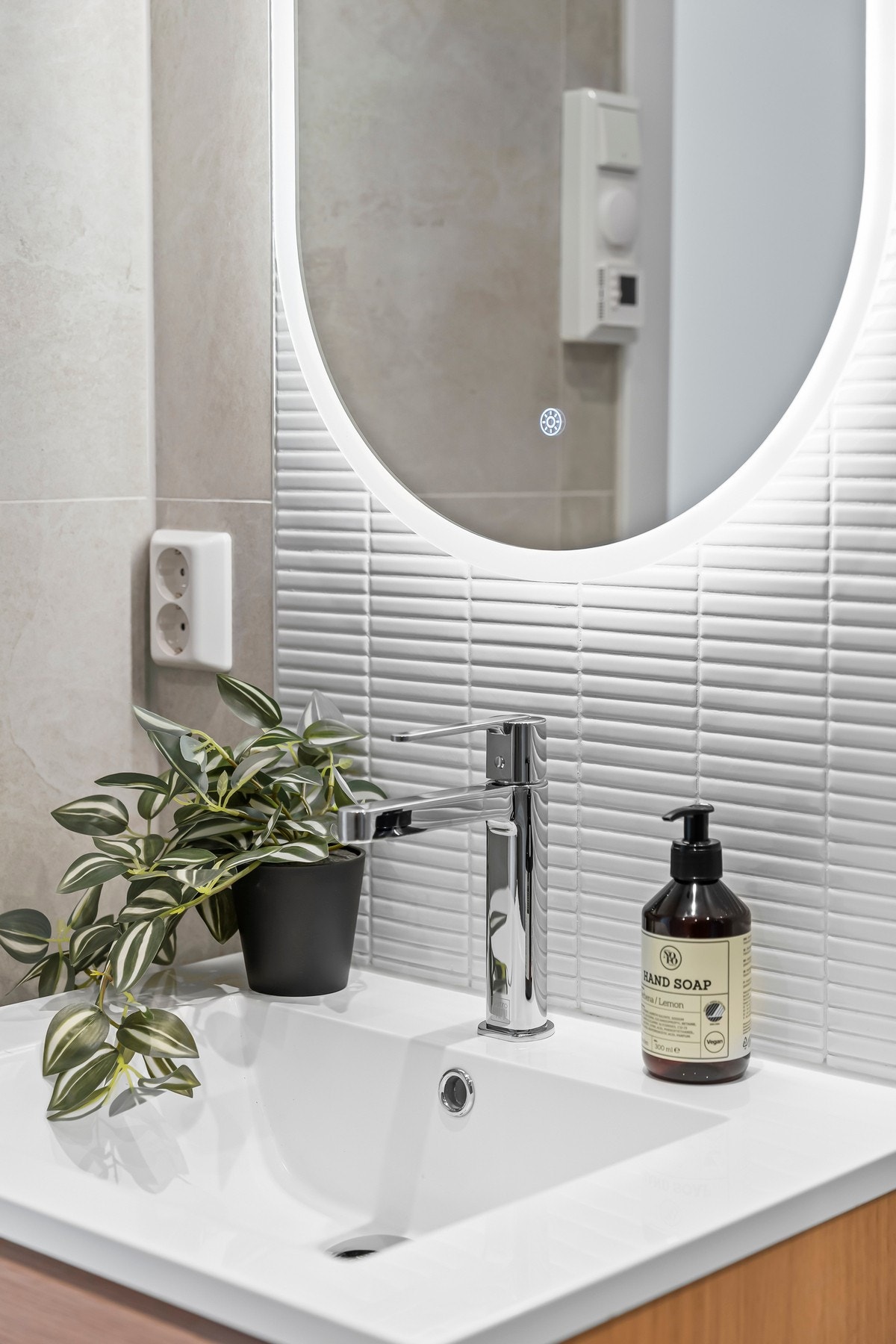 Servant med heldekkende topp og skuffeseksjon med lamellfronter i eikfarge, kombinert med ovalt speil med indirekte belysning og stilrent dusjhjørne med foldedører i glass. Galleribilde