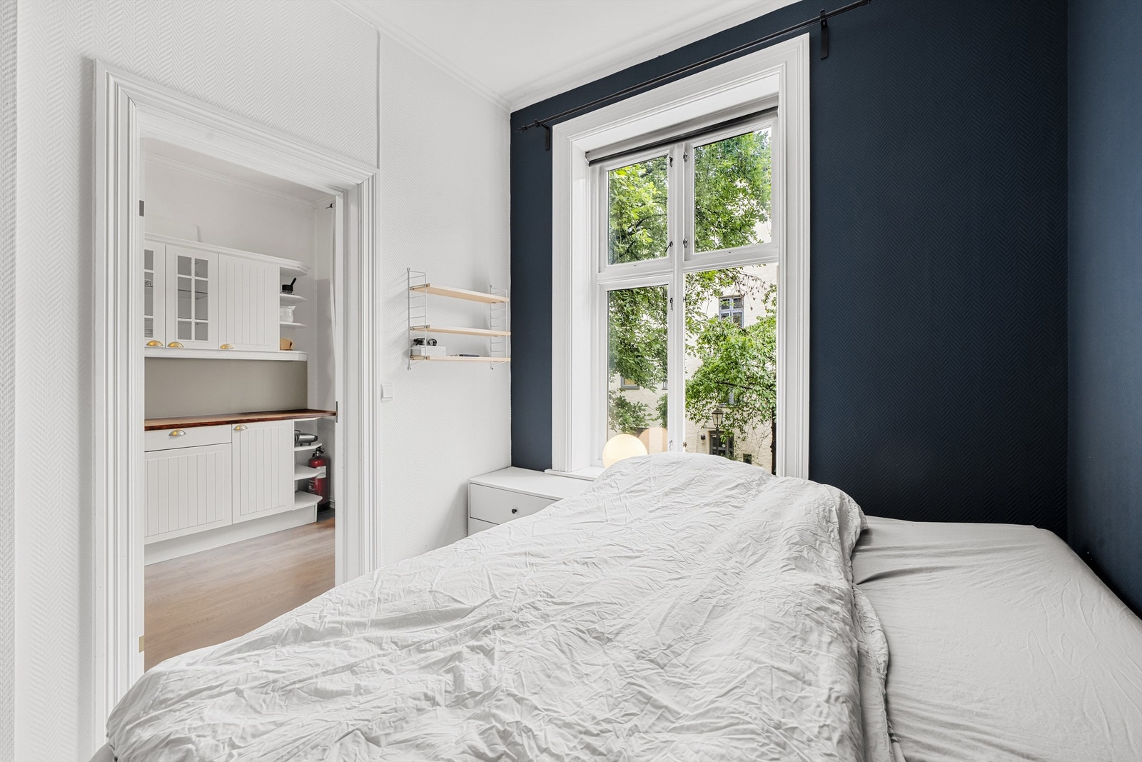 Et romslig og lunt soverom malt i en behagelig mørkeblå farge som skaper en rolig atmosfære. Galleribilde