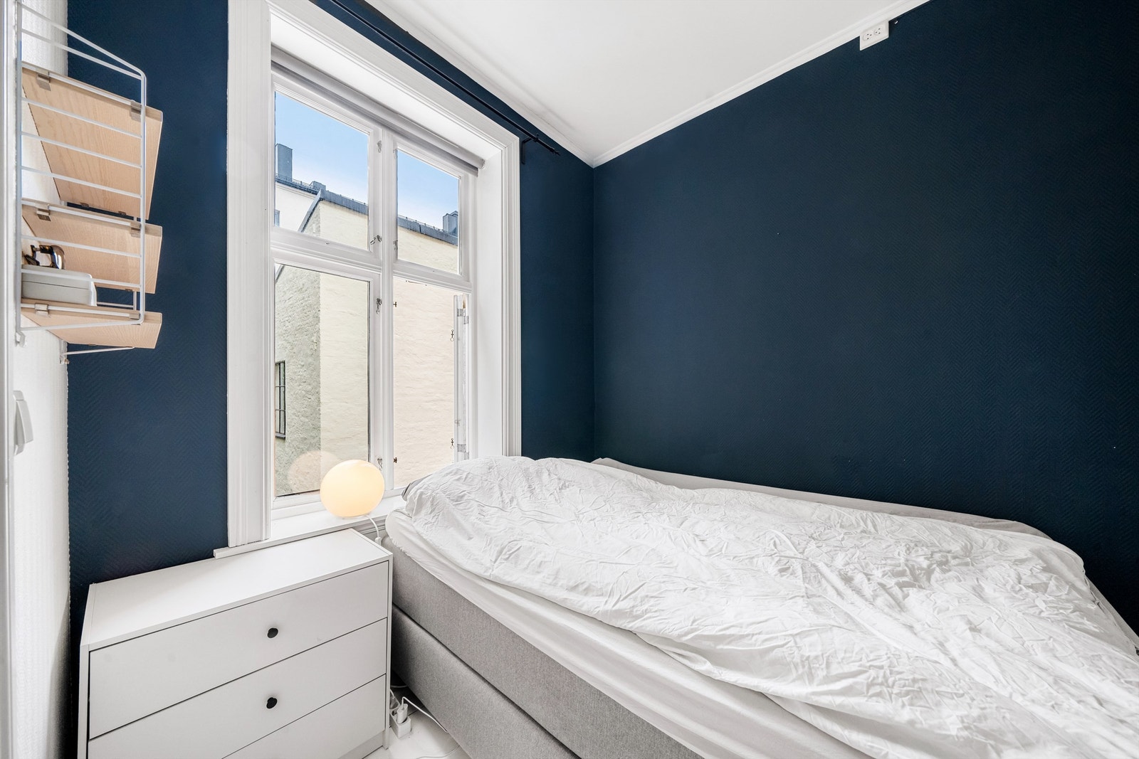 Stort vindu med utsyn mot stille bakgård gir rikelig med dagslys og balanserer de dype fargetonene i rommet. Galleribilde