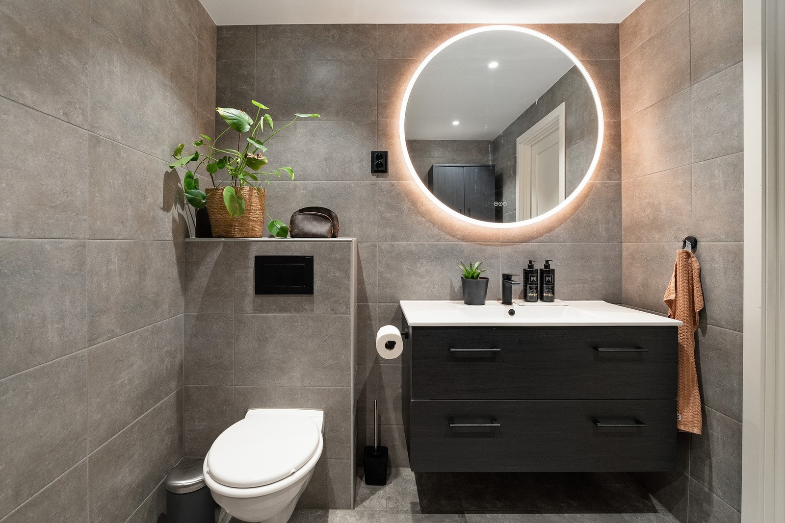 Rommet er innredet med vegghengt servantmøbel med skuffer og ovenpåliggende servant. Over servanten er det veggmontert speil med integrert belysning. Galleribilde