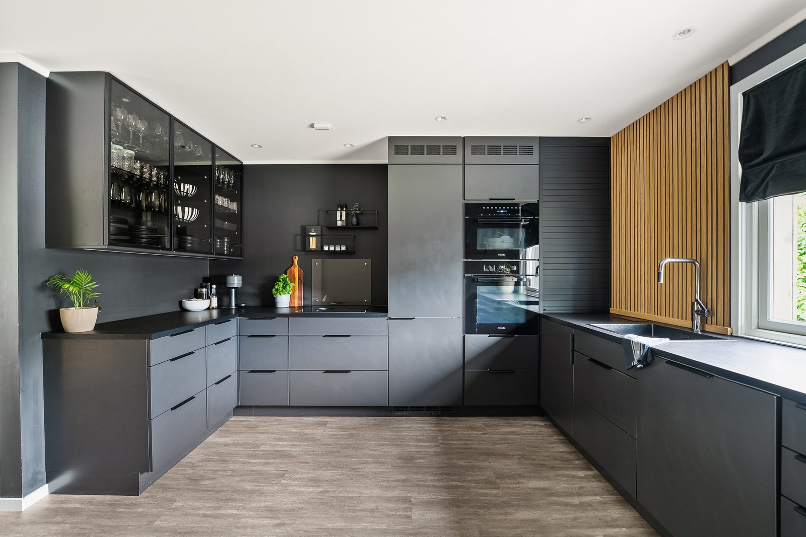 Moderne, åpen kjøkkenløsning fra 2022 med mørke slette fronter og laminat benkeplate. Galleribilde