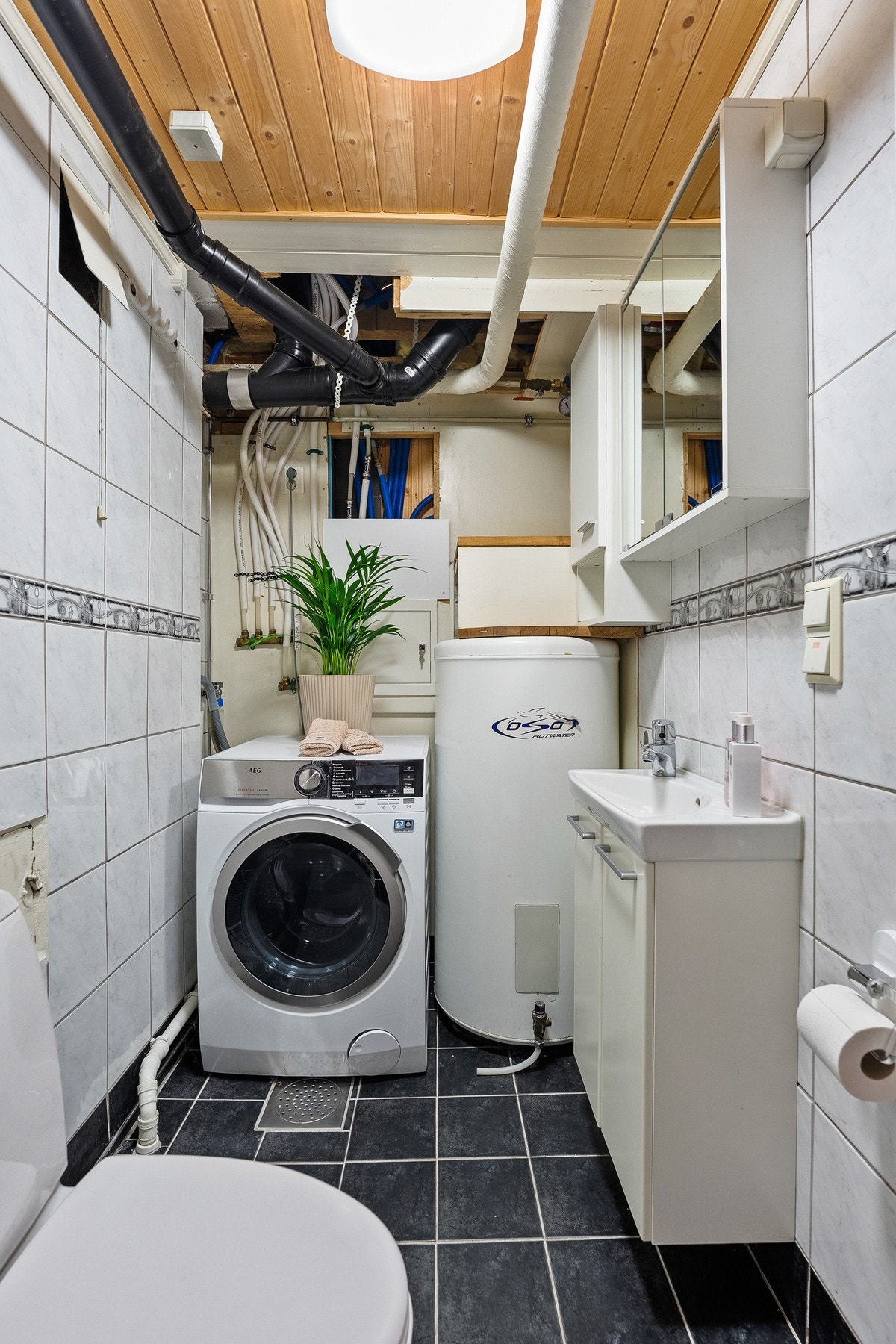 I tillegg finnes gulvstående toalett, dusjhjørne, opplegg for vaskemaskin samt plassering av varmtvannsbereder. Galleribilde