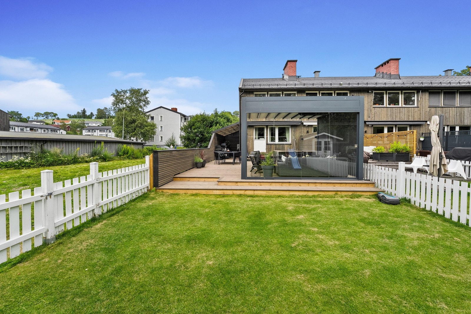 Den har direkte tilknytning til en lettstelt hage som gjør det enkelt å kombinere terrasselivet med lek og aktiviteter på gresset. Galleribilde