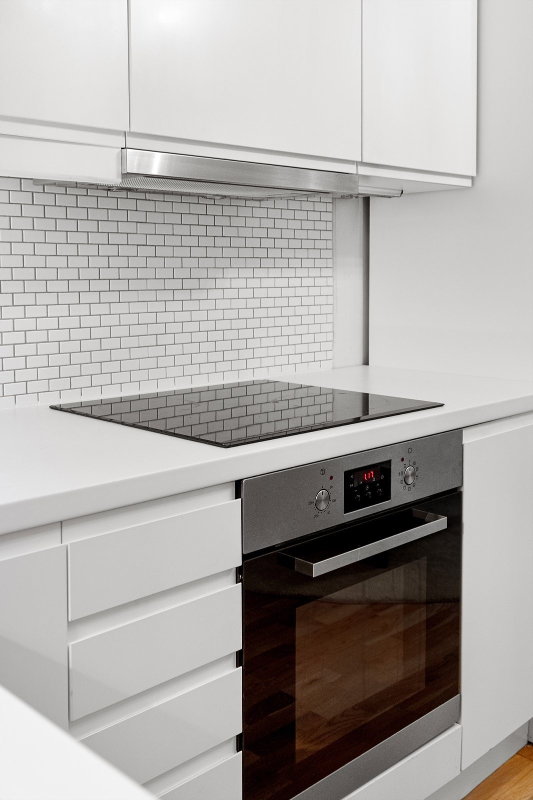 Glatt laminert kjøkkeninnredning, fliser mellom overskap, laminert benkeplate og integrerte hvitevarer. Galleribilde