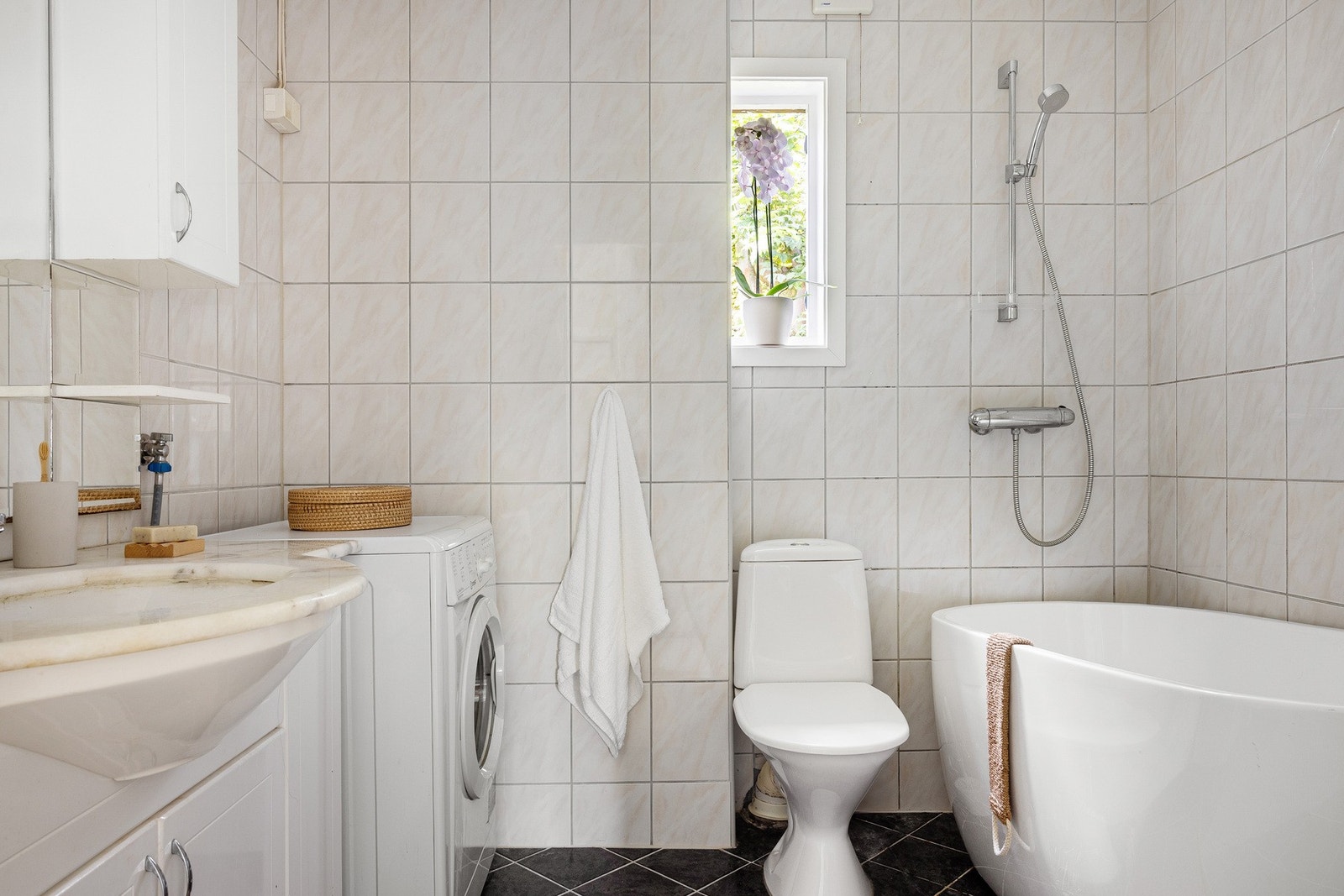Rommet er innredet med badekar med dusjløsning, toalett, baderomsinnredning og opplegg for vaskemaskin. Galleribilde