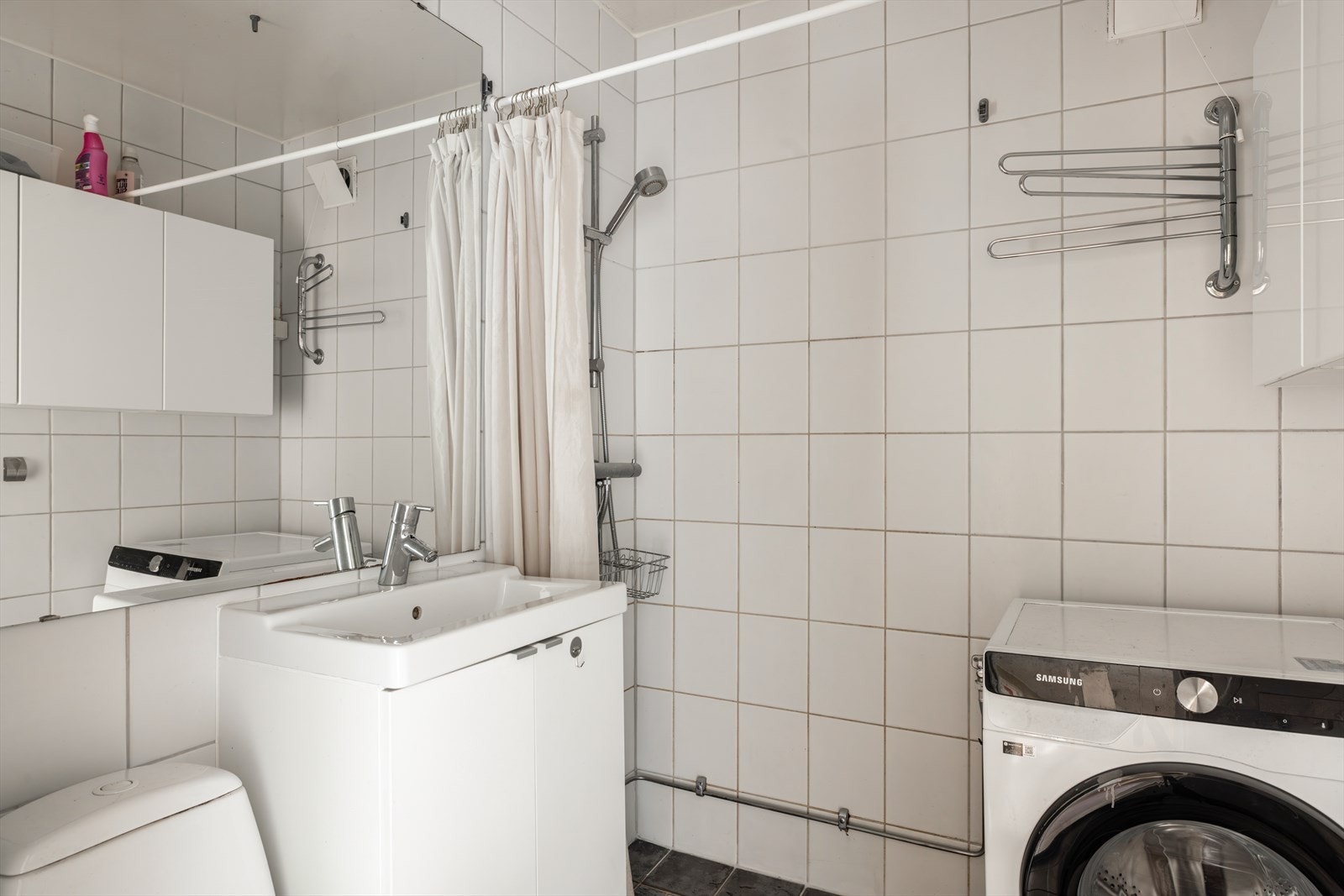 Praktisk kombinert bad og vaskerom med flislagte gulv og vegger, samt malt overflate i himling. Galleribilde