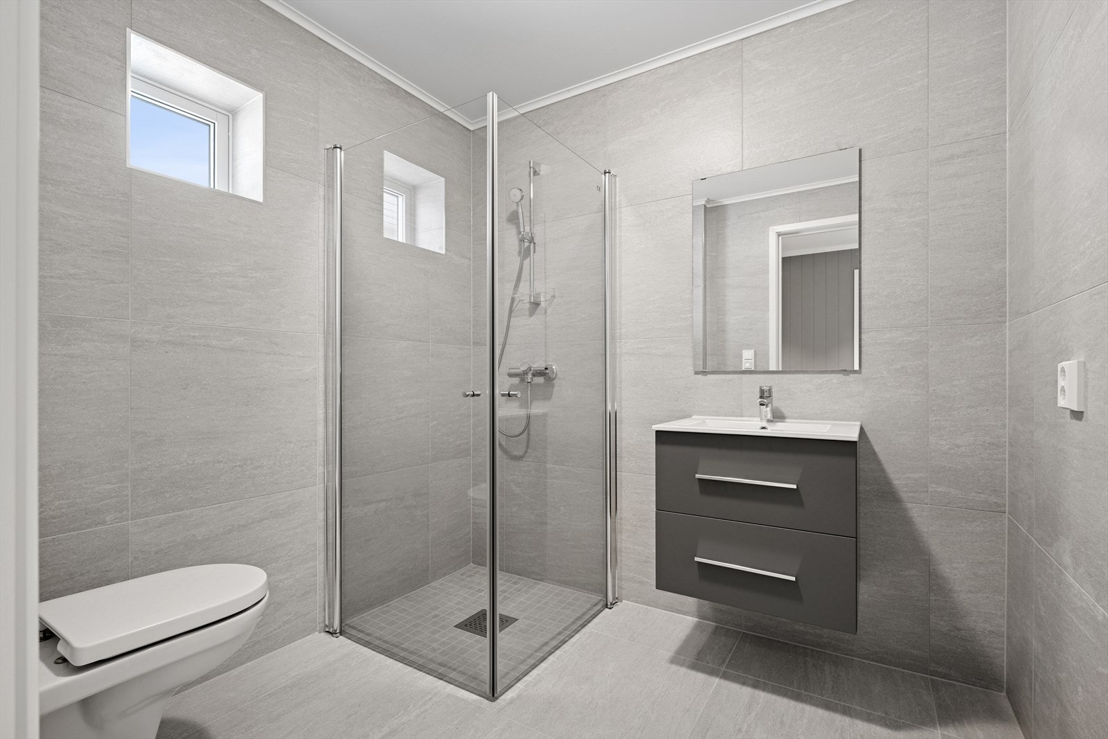 Flott flislagt bad, med vegghengt toalett, dusjnisje og baderomsmøblement. Galleribilde