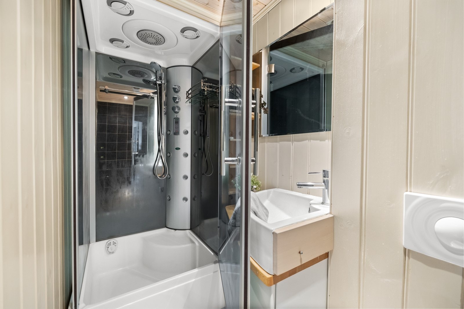 Rommet er innredet med vegghengt toalett, servant med underskap og dusjkabinett. Galleribilde