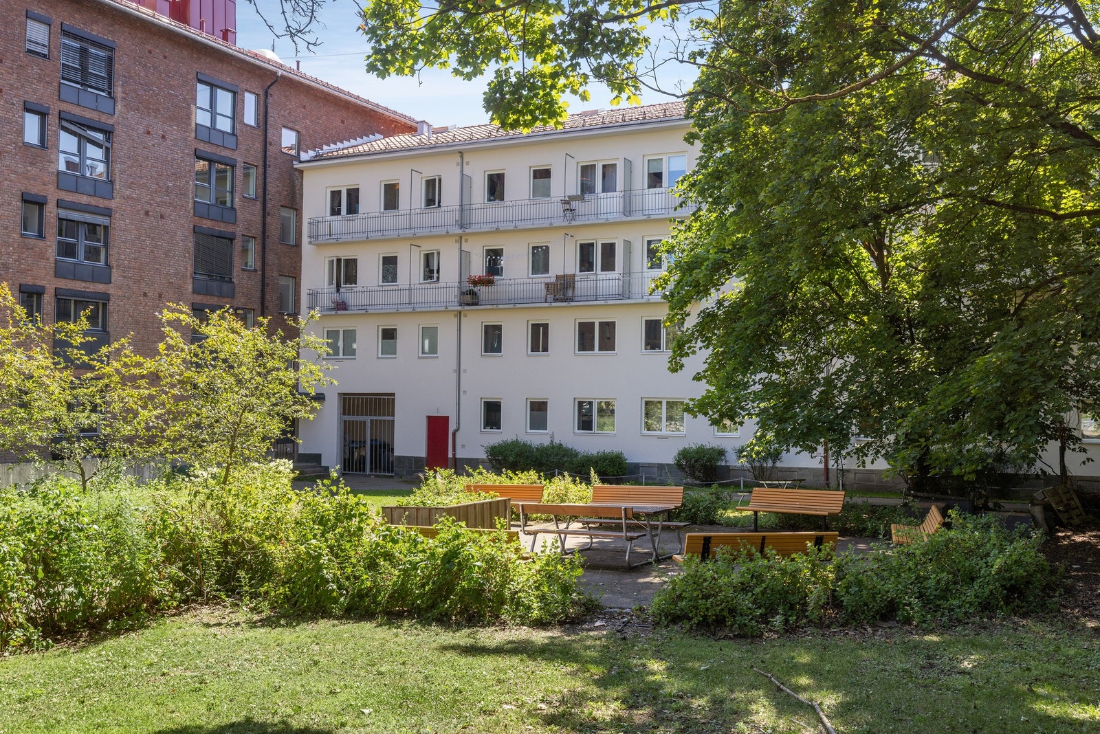 Gårdsrommet er pent opparbeidet med frodige grøntområder og hyggelige sittebenker som innbyr til avslapning og sosialt samvær. Galleribilde