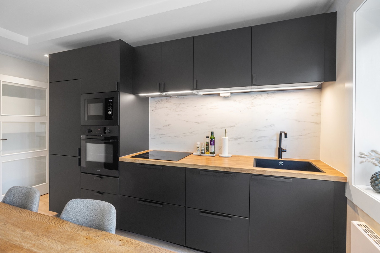 Kjøkkenet er utstyrt med integrerte hvitevarer, herunder komfyr, mikrobølgeovn, induksjonstopp, oppvaskmaskin, kombiskap og avtrekksvifte med kullfilter. Galleribilde