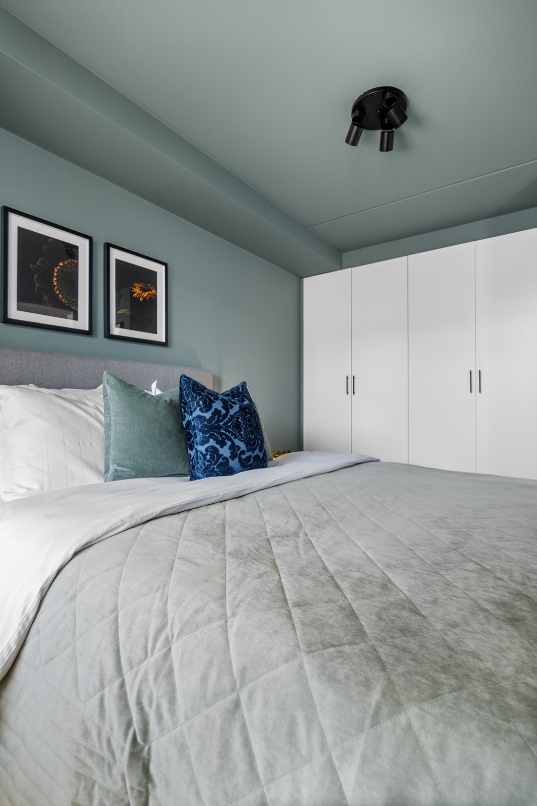 Den dempede blåfargen på soveromsveggen fungerer som en fin kontrast mot overflatene ellers i rommet. Galleribilde