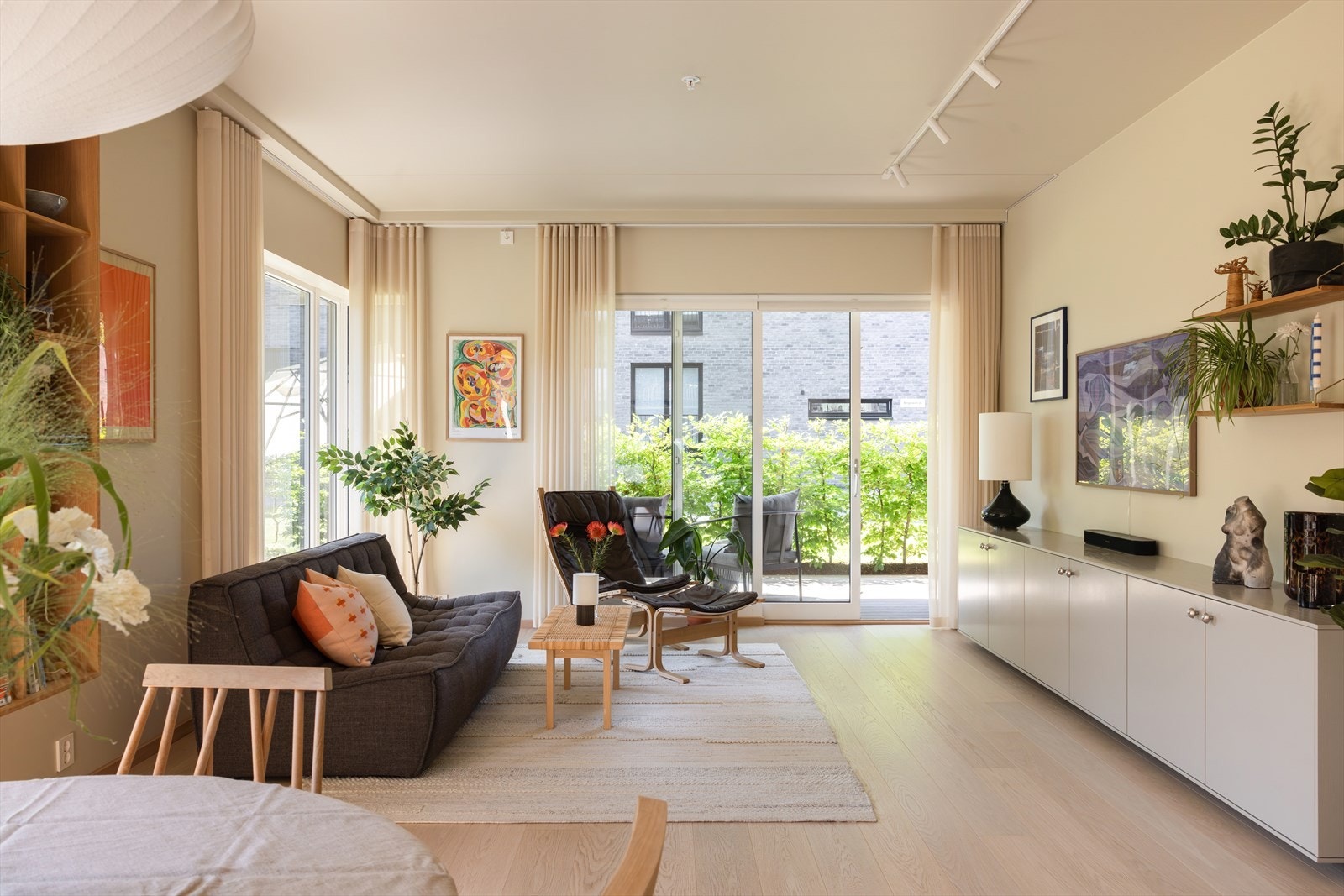 Det er montert spotskinne i himlingen, plisségardiner på vinduer, samt takskinner til gardiner på de største vinduene og terrassedørene mot enden av rommet. Galleribilde