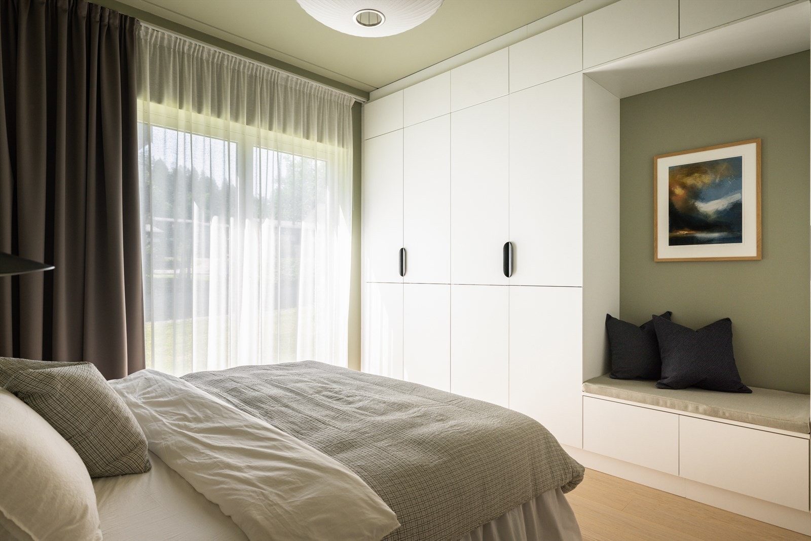 En tidløs, plassbygd garderobeløsning fra Kvik er montert fra gulv til tak, med hvite skapfronter, skuffer og en praktisk benk. Galleribilde