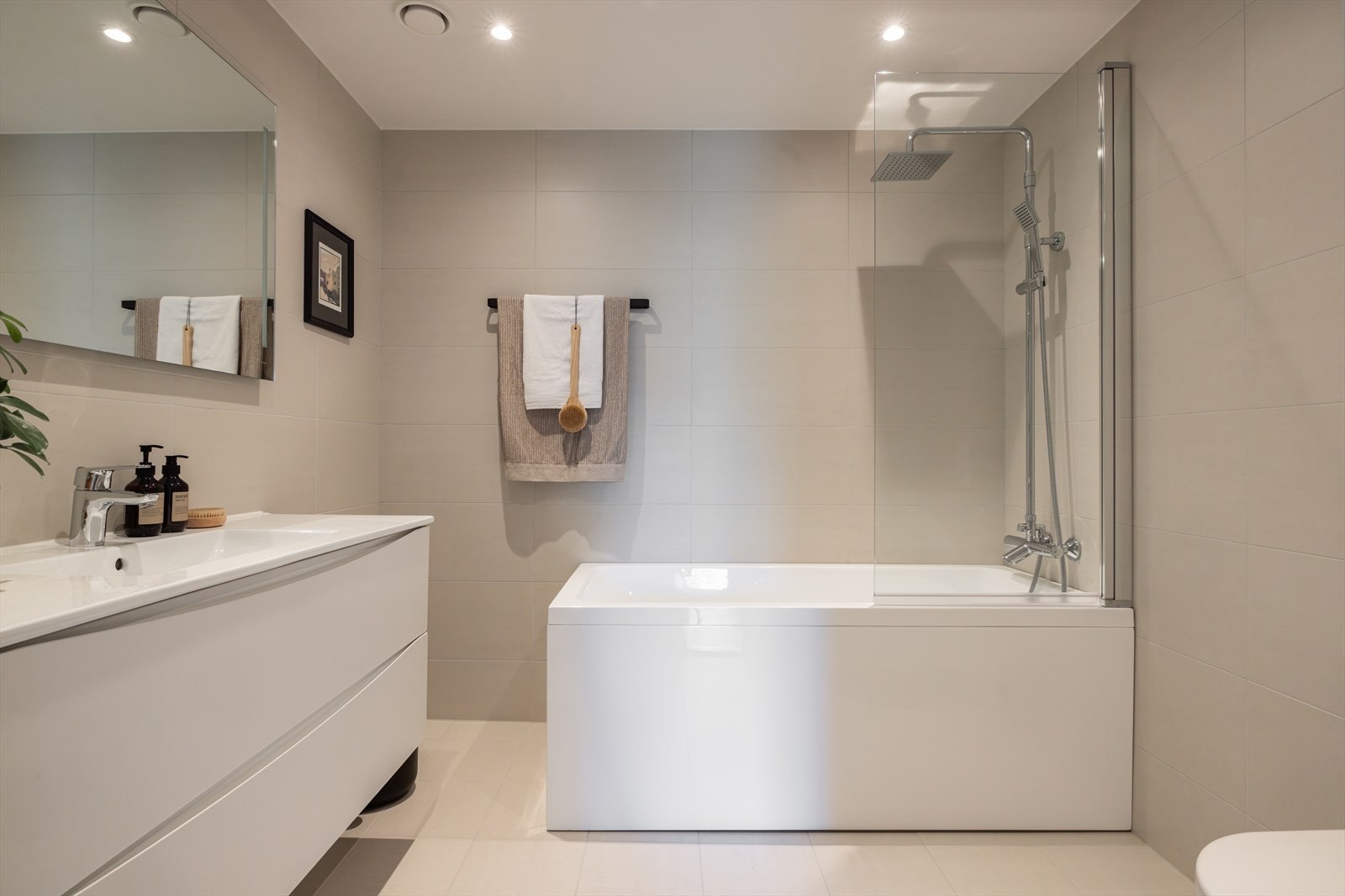 Leiligheten har to delikate bad og et separat vaskerom. Bad 2 har adkomst fra gangen utenfor soverom 2 og 3. Badet har lysbeige fliser på gulv og vegger, varmekabler og downlights. Galleribilde