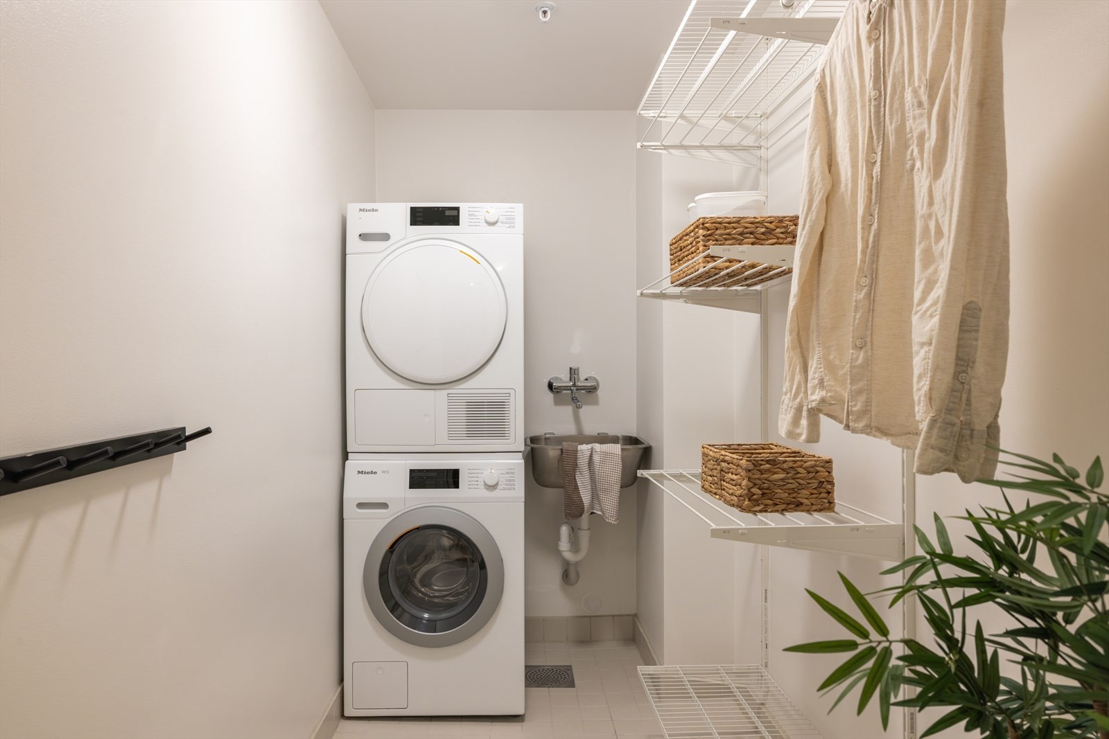 Vaskerommet har fliser på gulv med gulvvarme, lysmalte, glatte veggflater og listefri himling. Rommet er innredet med flere vegghyller, vaskekum i stål og opplegg for vaskesøyle. Galleribilde