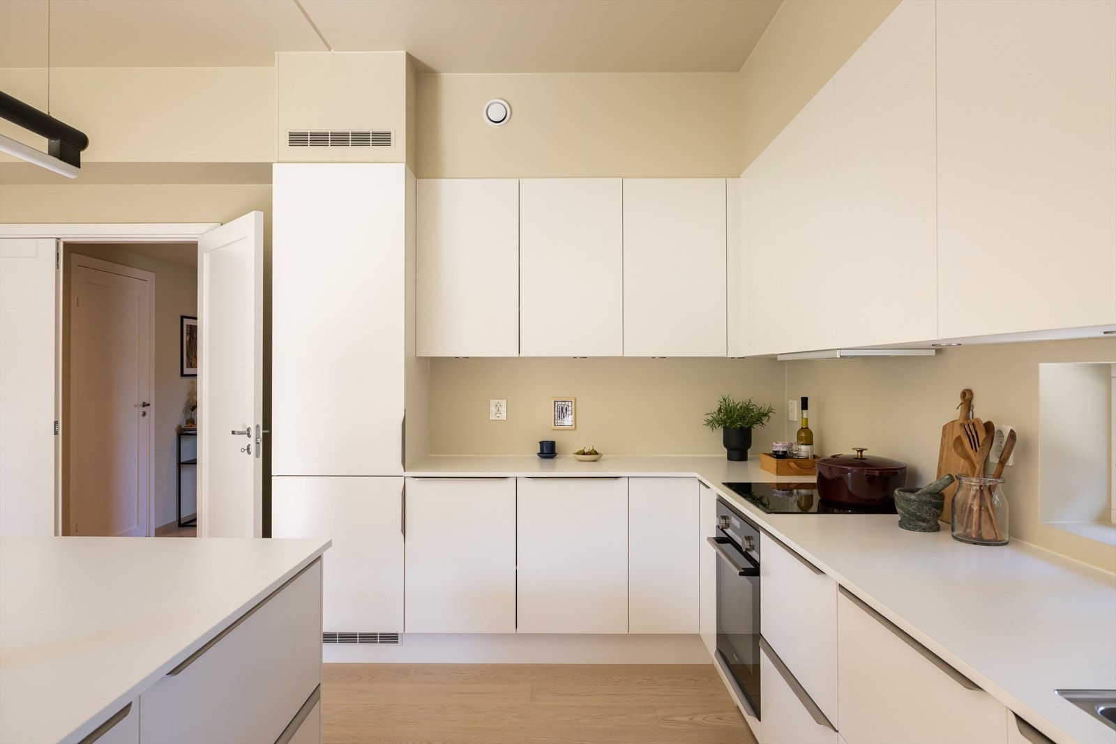 Kjøkken fra Sigdal med lyse, glatte fronter og matchende laminatbenkeplate med planlimt stålvask. Stilrent uttrykk og god plass til spisebord mot stuen. Integrerte hvitevarer - stekeovn, induksjonstopp, oppvaskmaskin, kjøleskap, fryser og ventilator. Galleribilde