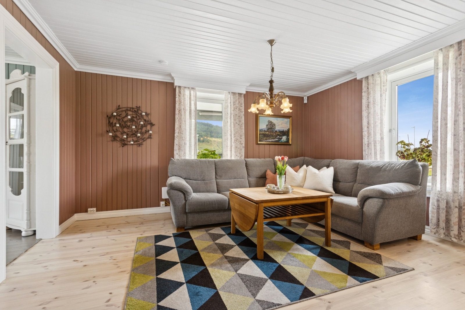 Stuen ligger i en delvis åpen løsning mot kjøkkenet, noe som skaper en luftig og sosial romfølelse samtidig som man bevarer en viss rominndeling. Galleribilde