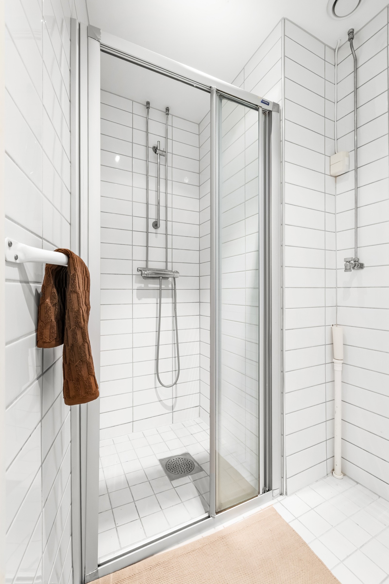 Det er opplegg for vaskemaskin. Badet inneholder et servantskap med speilskap over, et vegghengt toalett og en dusjsone med skyvedør i glass. Galleribilde