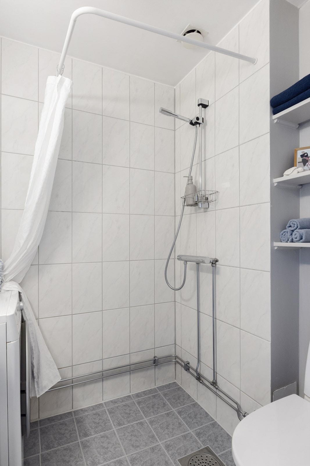 Badet er utstyrt med dusjsone, klosett (nytt i 2021), vegghengt servant med speil og overskap med glatte fronter Galleribilde