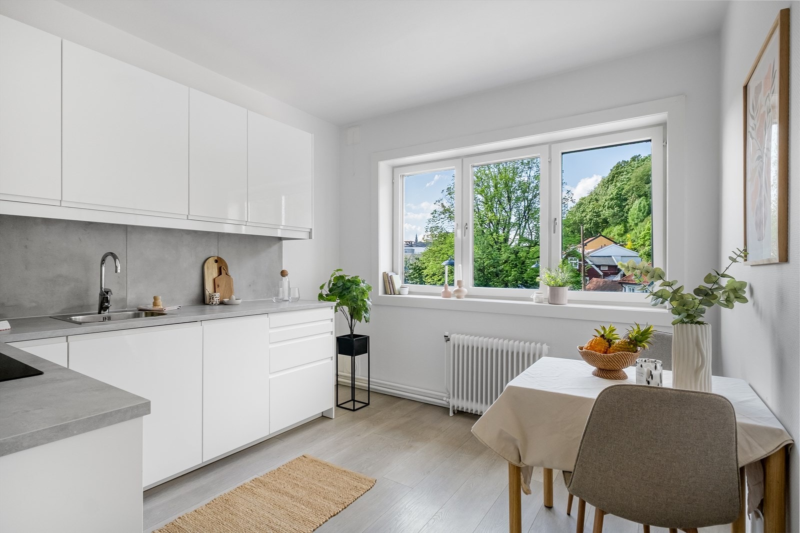 Leiligheten har et moderne kjøkken med hvite glatte fronter og integrerte hvitevarer. Rommet har god plass til spisebord. Store vindusflater sikrer optimale lysforhold. Galleribilde