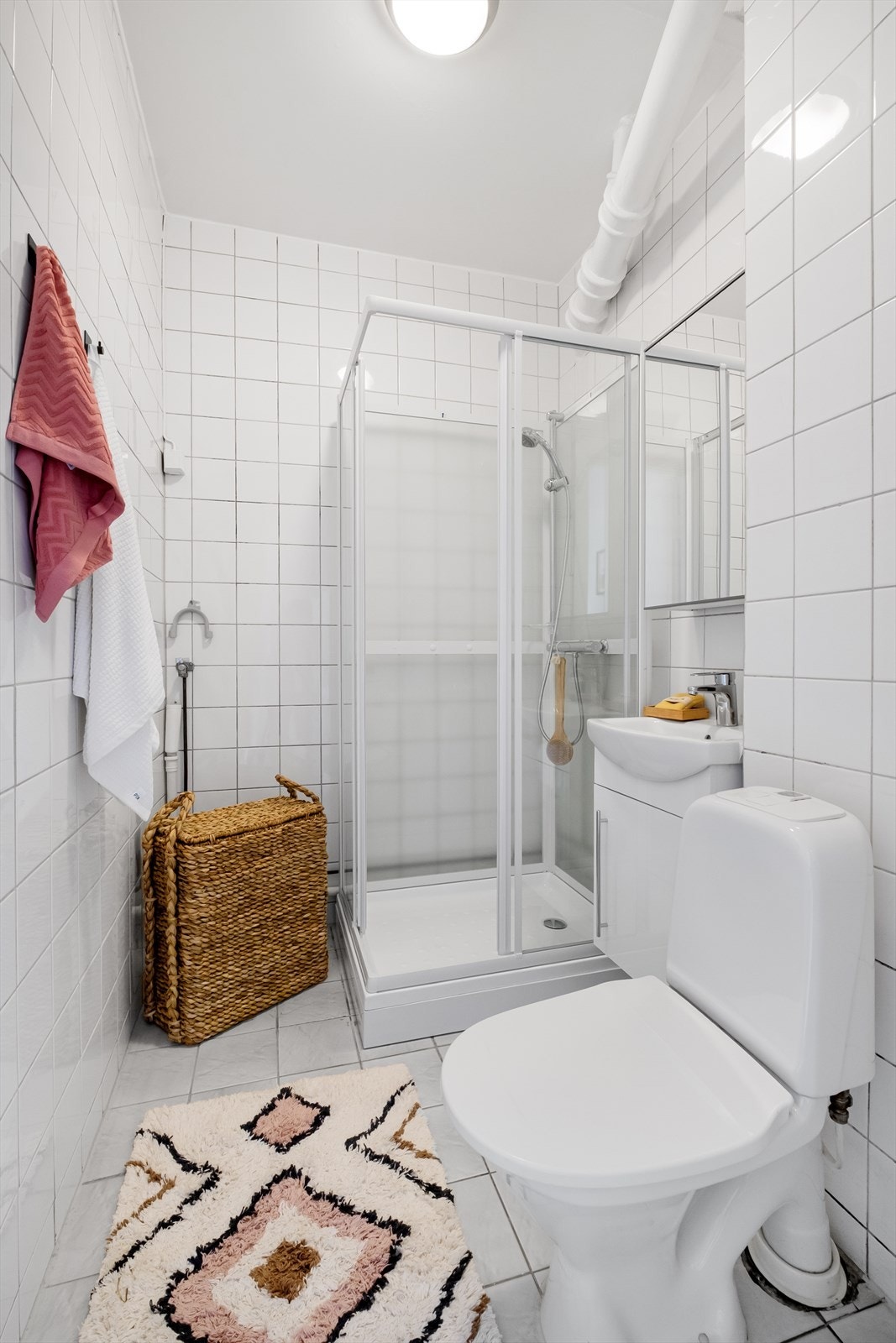 Flislagt bad med gulvstående toalett, dusjkabinett, servantinnredning med underskap og vegghengt speilskap. Opplegg for vaskemaskin. Galleribilde