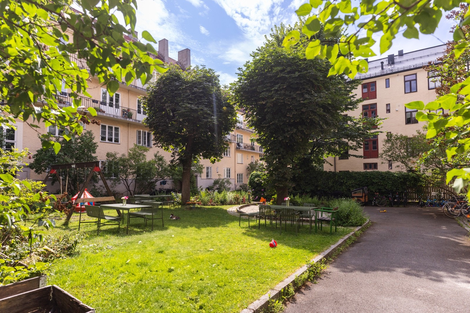 Idyllisk, rolig bakgård med flere sittegrupper og lekestatv. Galleribilde