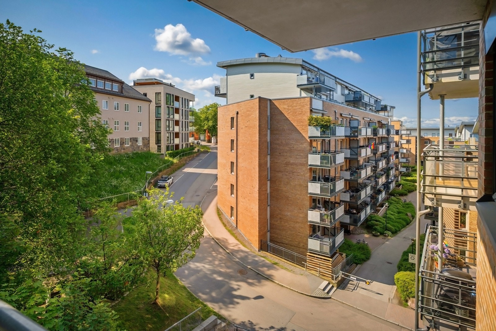 Fra balkongen ser man ut mot et skjermet grøntareal med frodige trær og plenareal utenfor nordsiden av bygget, noe som gir grønn idyll tett på. Mot øst strekker utsynet seg opp mot gatene og Sagene brannstasjon. Galleribilde
