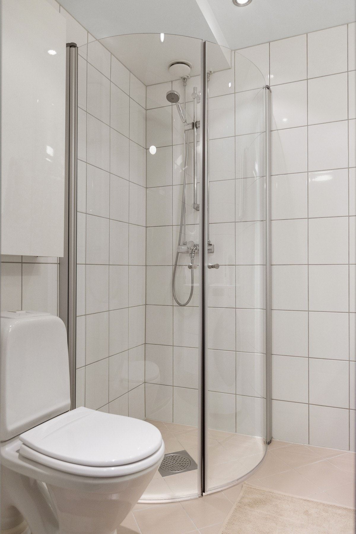 Dusjhjørne med innfellbare dusjvegger, toalett og servant med ettgreps blandebatteri i innredning. Galleribilde