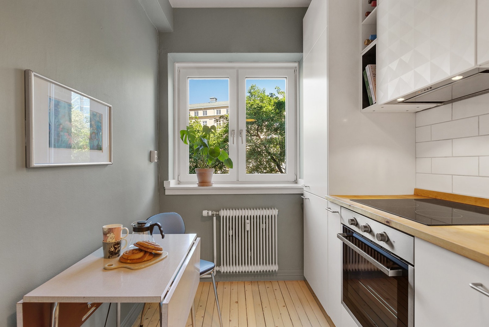 Pent kjøkken fra 2015 med fronter i hvit utførelse, heltre benkeplate, oppvaskkum, kullfilterventilator og fliser over benk. Galleribilde