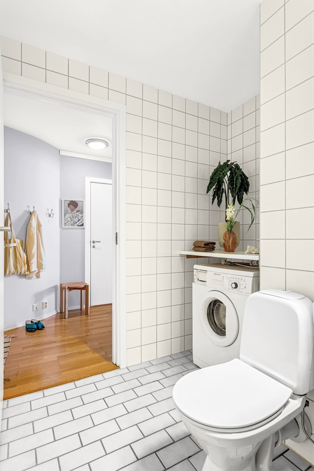 Badet inneholder frittstående toalett, dusj, servant med ett-greps blandebatteri og servantskap, samt opplegg for vaskemaskin. Galleribilde