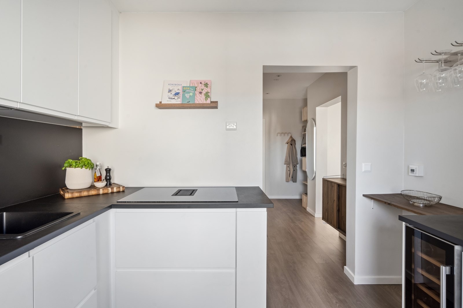 Innredningen består av hvite, slette fronter og benkeplate i laminat med oppvaskkum av kompositt. Integrerte hvitevarer som oppvaskmaskin, stekeovn og micro i høyskap, vinskap, samt platetopp med integrert avtrekk. Opplegg for side by side kjøleskap Galleribilde