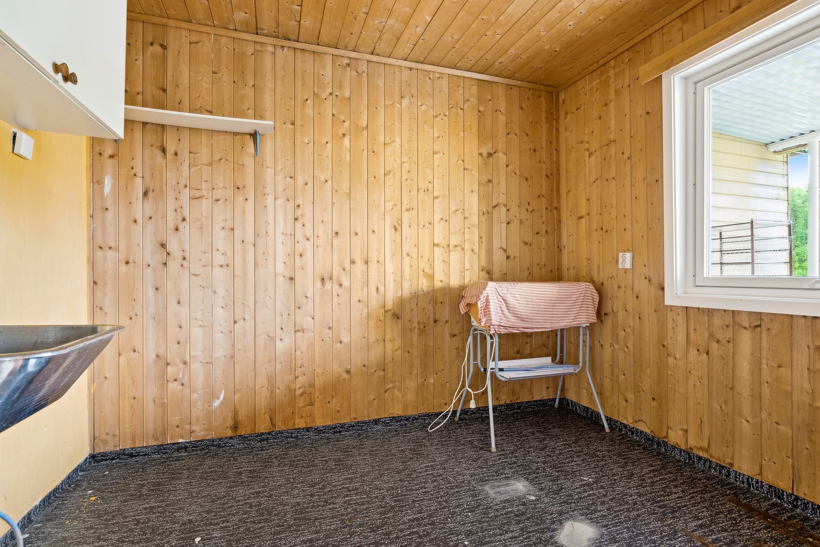 Praktisk vaskerom med belegg på gulv, utslagsvask og opplegg for vaskemaskin Galleribilde