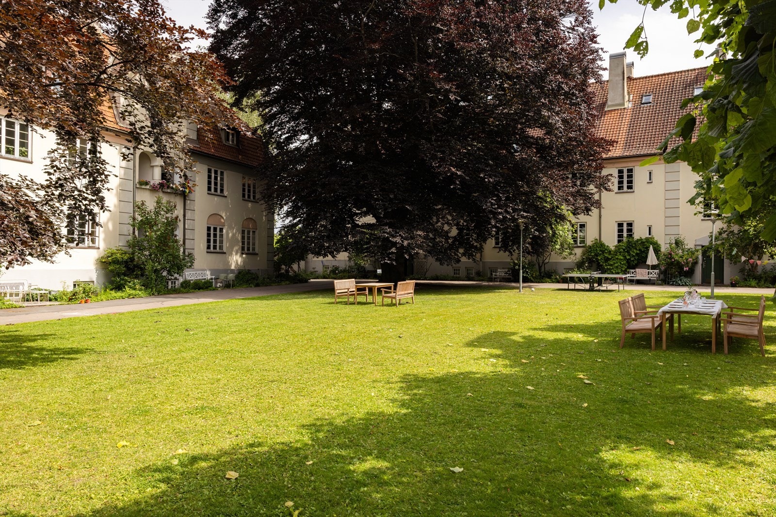 Bakgården er parkmessig opparbeidet med prydbusker, trær, benker og bordtennis-bord. Galleribilde