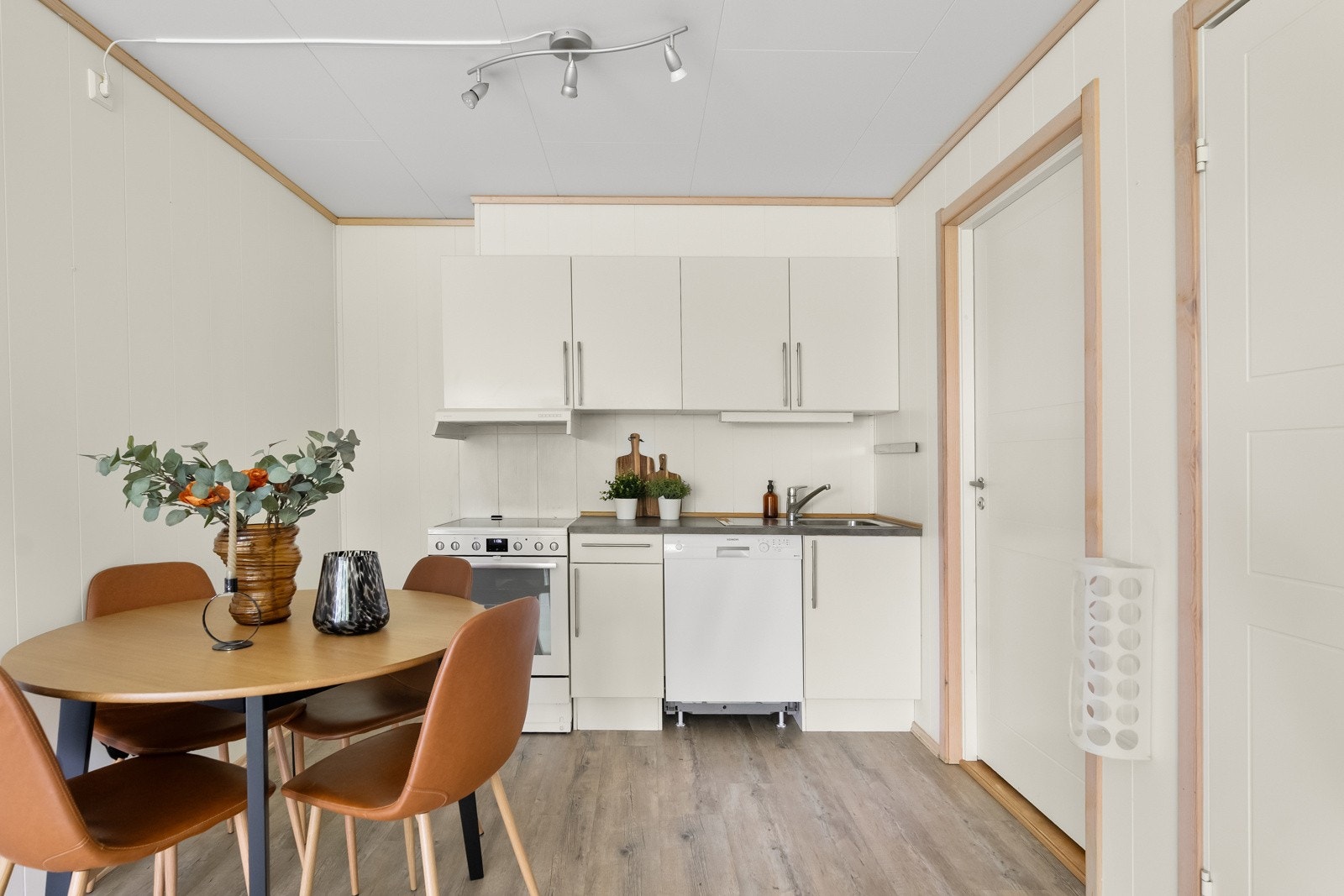 Fin avsatt plass til å sette inn et spisebord i nærhet til kjøkkenet. Stilrent kjøkken i åpen løsning mot stuen, fra 2009. Kjøkkeninnredning med hvite fronter og håndtak. Avsatt plass til kjøleskap. Galleribilde