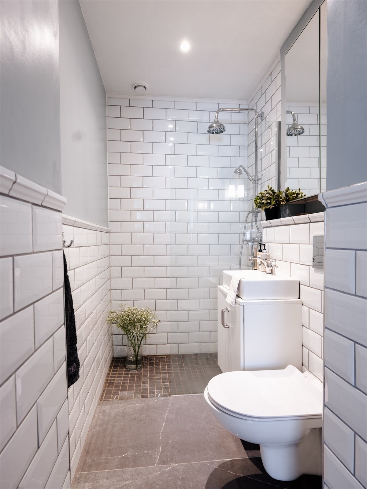 Badet er flislagt med mørke gulvfliser og mosaikk i dusjsonen, samt malte og flislagte vegger Galleribilde