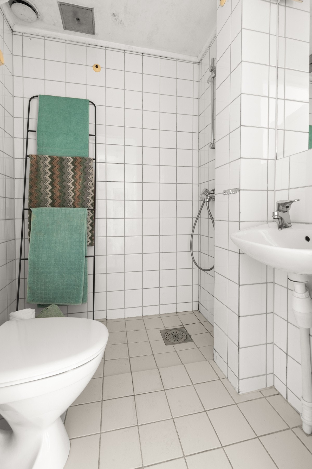 Eldre baderom med flis på gulv og nedsenket dusjsone. Galleribilde