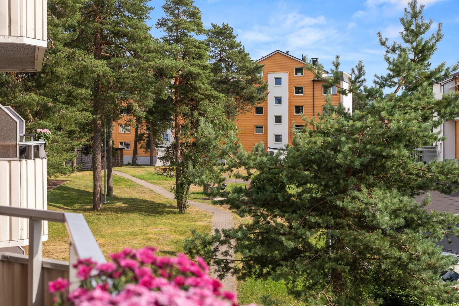 Fra balkongen er det hyggelig utsyn til grønne fellesarealer opparbeidet med plen, trær, hekker og asfalterte internveier. Galleribilde