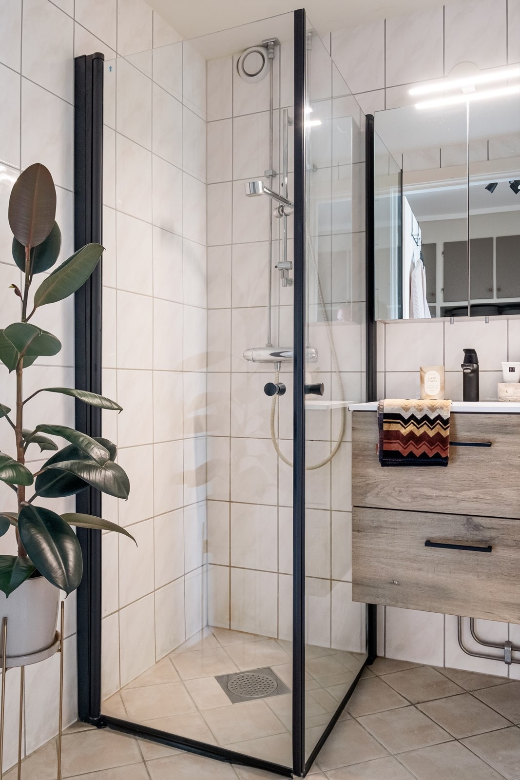 Badet er innredet med vegghengt klosett, servant på innredning og dusjhjørne med svingbare dører. Galleribilde